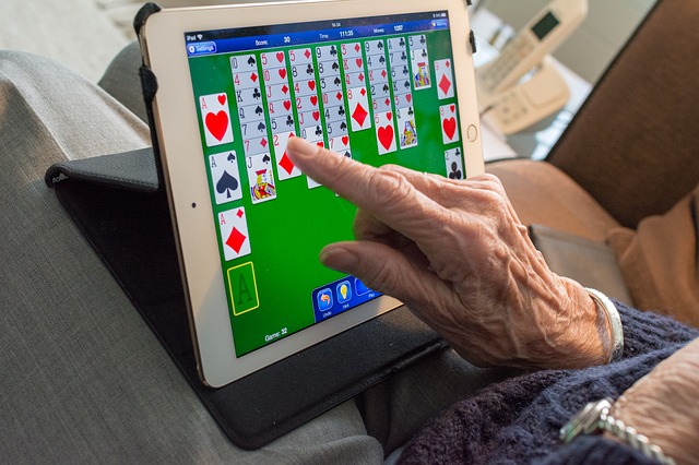 ruka seniorky hrající na tabletu